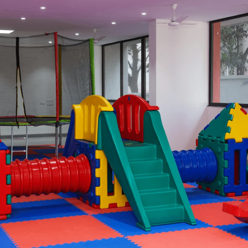 A colorful indoor play gym with a trampoline, tunnels, and a climbing slide.